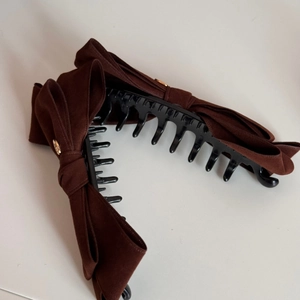 Detailed close-up of dark brown velvet bow banana clip with golden metal decorative buckle