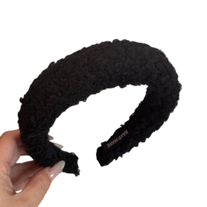 Plush lamb wool headband in black featuring a handmade label and high top design