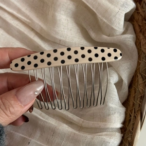 Detailed close-up of oval polka dot acetate hair comb with fourteen silver metal teeth
