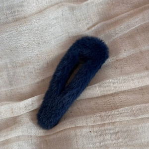 Detailansicht der plüschigen dunkelblauen Tropfen-Haarklammer auf Leinenhintergrund