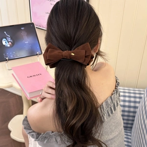 Elegant large brown velvet double bow hair clip with gold logo detail worn on low ponytail