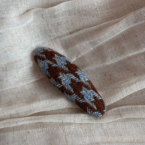 Detail of blue and brown houndstooth knitted triangular hair clip on linen background