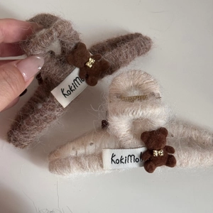 Detail showing plush teddy bear hair clips in brown and beige with golden bow ties