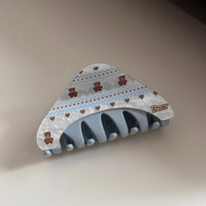 Detail view of acetate hair claw clip with bear print and blue heart patterns
