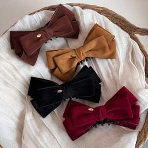 Detail of four large velvet bow banana clips in brown, yellow, black and burgundy