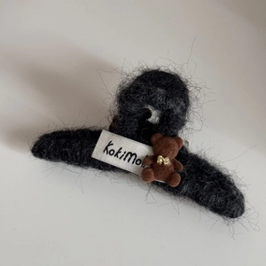 Detail of plush bear hair claw with black faux fur, golden bow, and branded KokiMo tag
