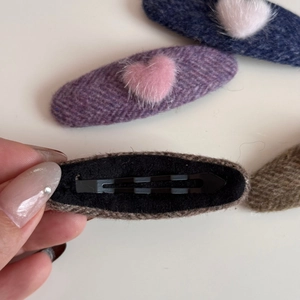 Detailed view of tweed fabric hair clip with plush heart and metal duckbill clip