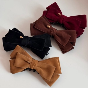 Detail of velvet bow banana clips in four colors featuring golden Love metal plate