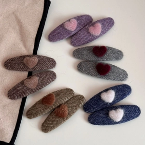 Close-up of heart-shaped plush hair clips with tweed fabric in diverse autumn colors