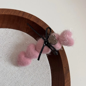 Detail einer rosa Plüsch-Herzspange mit schwarzer Schleife und funkelndem Straß-Herzchen