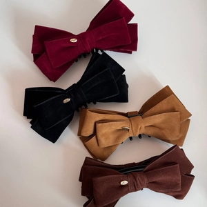 Flat lay of velvet bow banana hair clips in wine red, black, camel, and coffee colors
