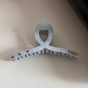 Detailed view of light blue acetate hair claw clip with bear print and Puppy text