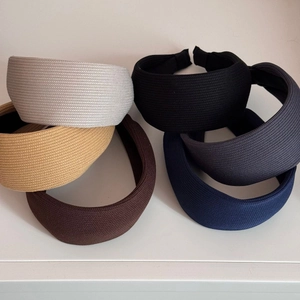 Stack of six knitted wide headbands in neutral colors like beige, brown, and grey