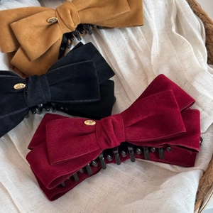 Detailed close-up of vintage velvet bow banana clips in camel, black, and wine red colors
