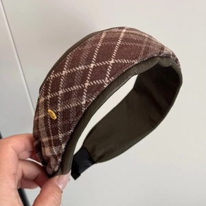 Detailed view of plaid wide headband featuring a gold metal Love tag and leather lining