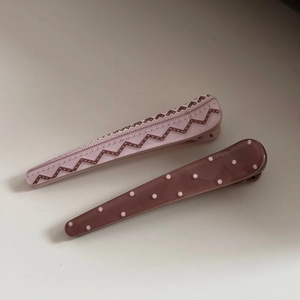 Detail of two acetate hair clips featuring contrast patterns with dots and zigzags