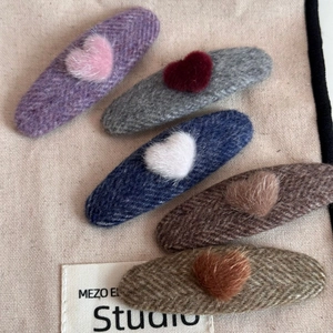 Detail of five oval fabric hair clips with plush hearts in autumn winter wool textures