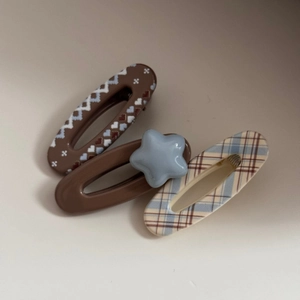 Detail view of acetate hair clips featuring heart, star patterns, and classic blue plaid