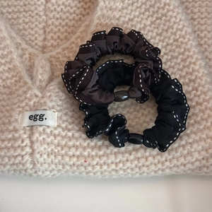 Detailed macro view of pleated ribbon hair ties with white stitch edges and oval buckles