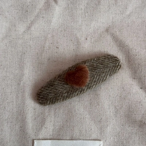 Detail of oval herringbone fabric hair clip with a plush brown heart decorative center