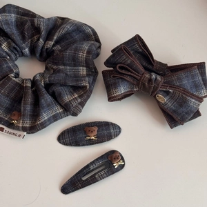 Détail d'accessoires cheveux à carreaux bleus avec ours brun et noeuds dorés