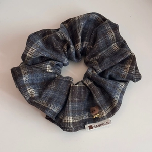 Détail d'un chouchou à carreaux bleu et gris avec petit ours en peluche et étiquette
