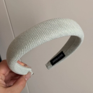 Close-up of light green knit fabric texture and handmade label on padded headband