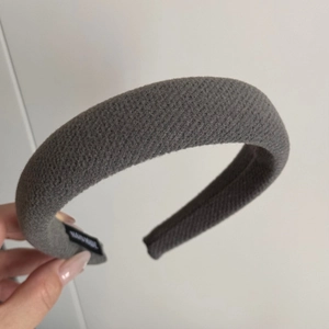 Detail of grey knitted fabric headband showing the texture and handmade woven label