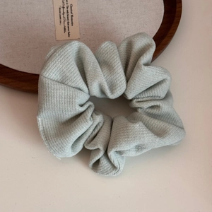 Close-up of mint green ribbed fabric scrunchie on white background with rustic decor