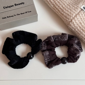 Detailed macro view of black and brown plush hair scrunchies with glossy black beads
