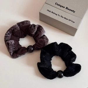 Detail of plush velvet hair scrunchies in black and coffee brown with central bead