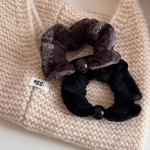 Close-up of plush velvet hair scrunchies with black beads on a beige knit background