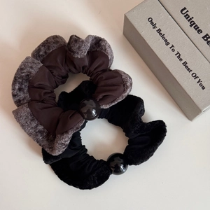 Close-up of plush velvet scrunchies with large black beads in brown and black colors