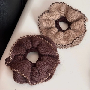 Dettaglio di elastici per capelli in maglia caffè e beige con bordo ondulato e coste