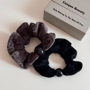 Detail view of plush scrunchies in black and grey with shiny decorative round beads