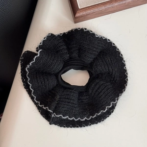 Dettaglio di un grande elastico scrunchie in maglia nera con bordi argentati