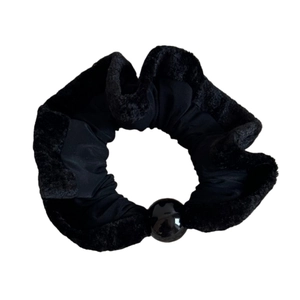 Elegant black scrunchie with plush trim and large decorative bead for a minimalist hair look