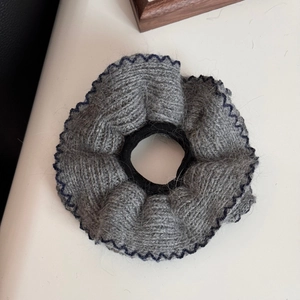 Dettaglio di scrunchie in maglia grigia con bordo overlock in blu scuro intenso