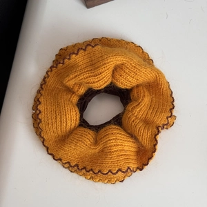 Dettaglio dell'elastico per capelli in maglia giallo con bordo ricamato a onde marroni