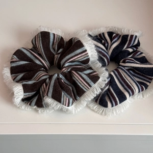 Detail of two oversized striped knit scrunchies with white feathered fringe trim