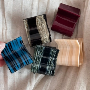 Detail view of five assorted acetate hair claws showing diverse marble textures and patterns