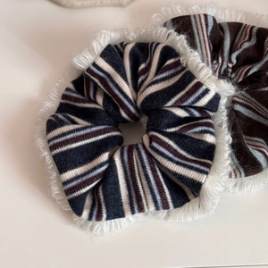 Detail of knitted striped scrunchie with soft white fuzzy fringe edge and thick texture