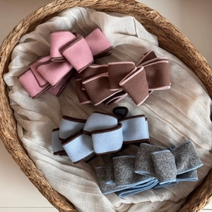 Retro faux suede bow hair clips in four soft colors displayed in a rustic basket