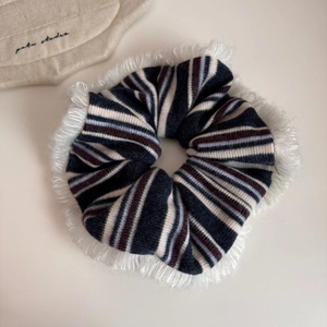 Detailed close-up of a striped knit scrunchie with soft white faux fur trim and texture
