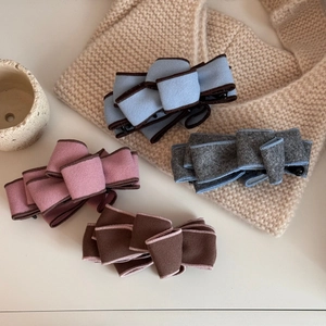 Detail of layered suede bow hair clips in blue, pink, grey and brown colors