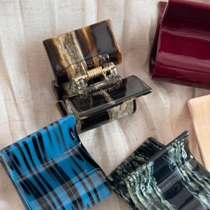 Detailed close-up of tortoise shell and marble acetate hair claws with gold springs