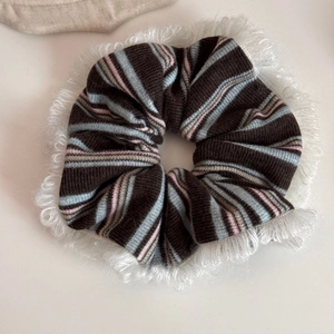 Close-up of striped knit fabric texture and white faux fur trim on large hair scrunchie
