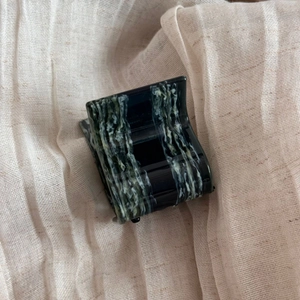 Detailed macro view of small square acetate claw clip with dark green marble pattern texture