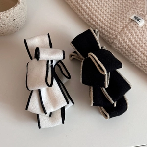Detail of multi-layered suede bow banana clips with premium contrast stitching and wool texture