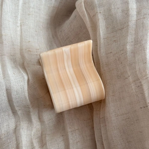 Detail of small tortoise shell acetate hair claw clip on neutral textured linen fabric